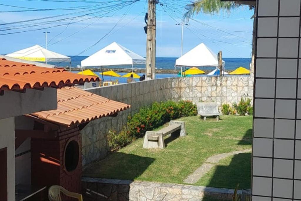 a backyard with a bench and umbrellas on the beach at Aconchegante Apt FRENTE AO MAR in Barra de São Miguel