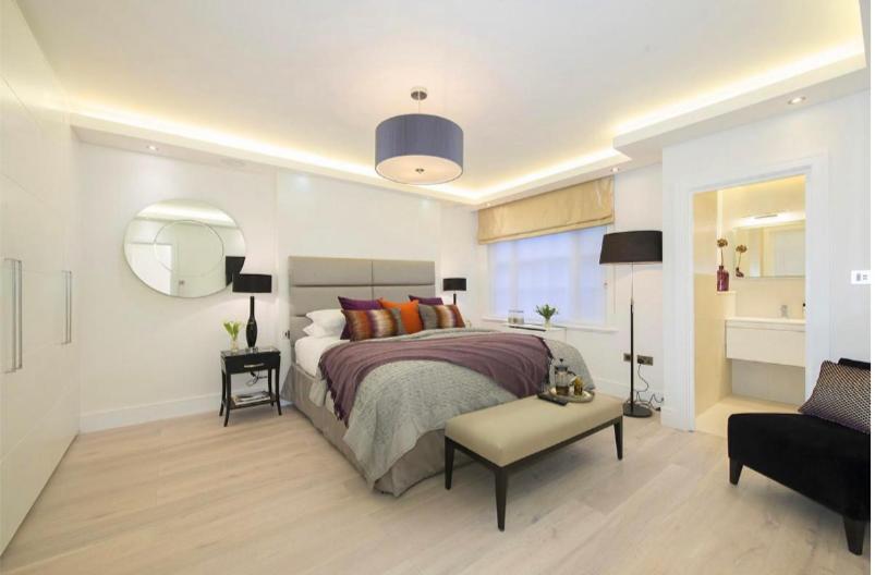 a bedroom with a bed and a chair and a mirror at Hestia Travel Mayfair London in London