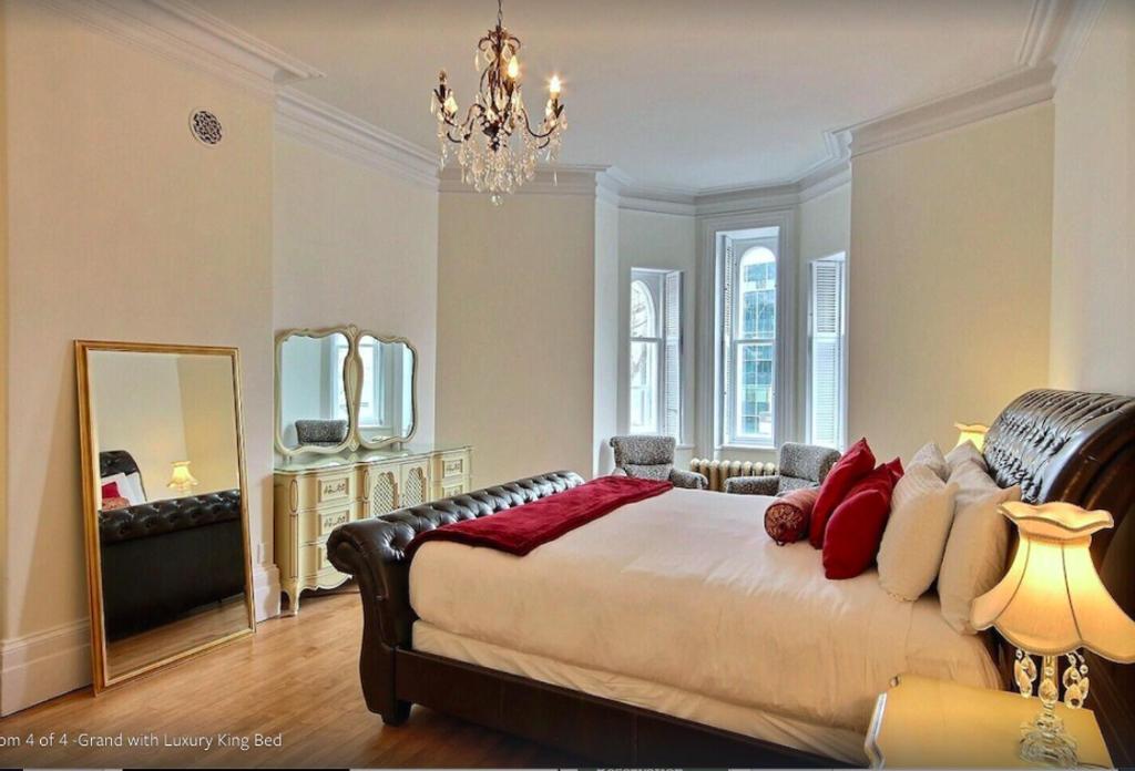 een slaapkamer met een groot bed en een spiegel bij Les Maisons Montcalm in Québec