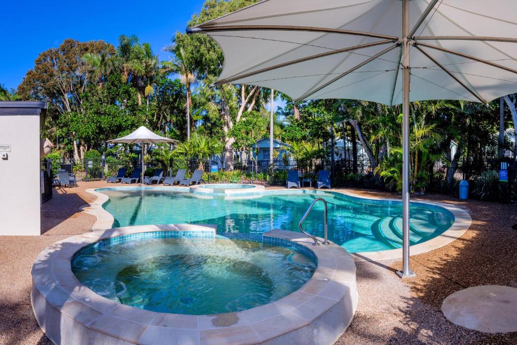 a large swimming pool with an umbrella and an outdoor pool at BIG4 Tasman Holiday Parks - Ballina in North Creek