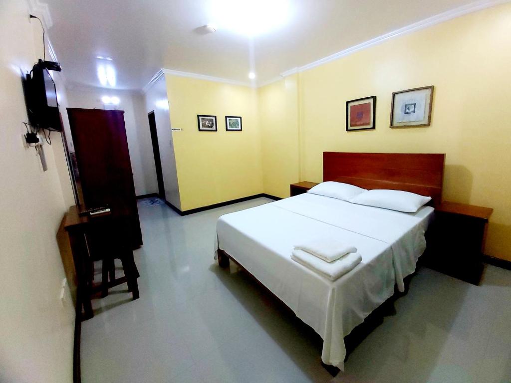 1 dormitorio con 1 cama blanca grande y TV en Golden Pension House,Palawan en Puerto Princesa