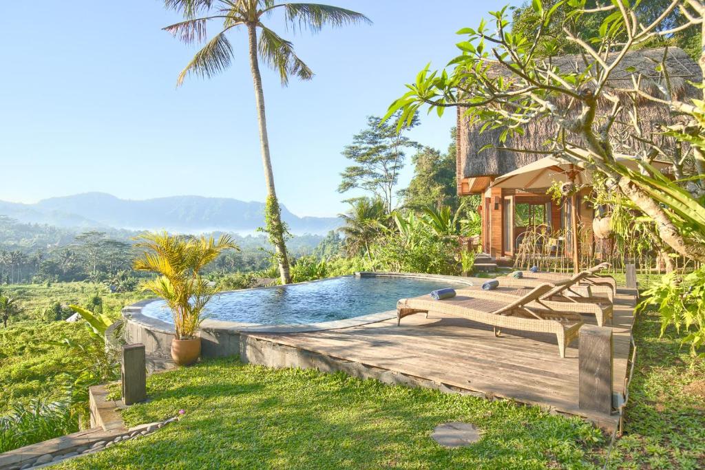an outdoor pool with a deck and a house at Romantic Barn with Mt. Agung Views in Sidemen