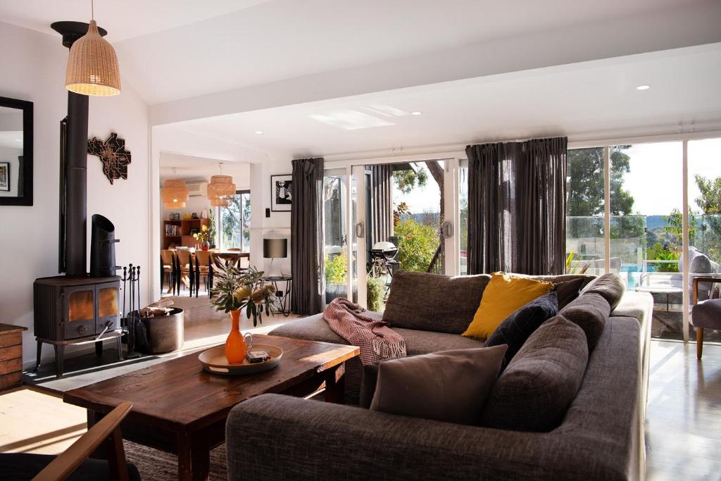 a living room with a couch and a table at Cornish Hill House - stunning views with pool in Daylesford