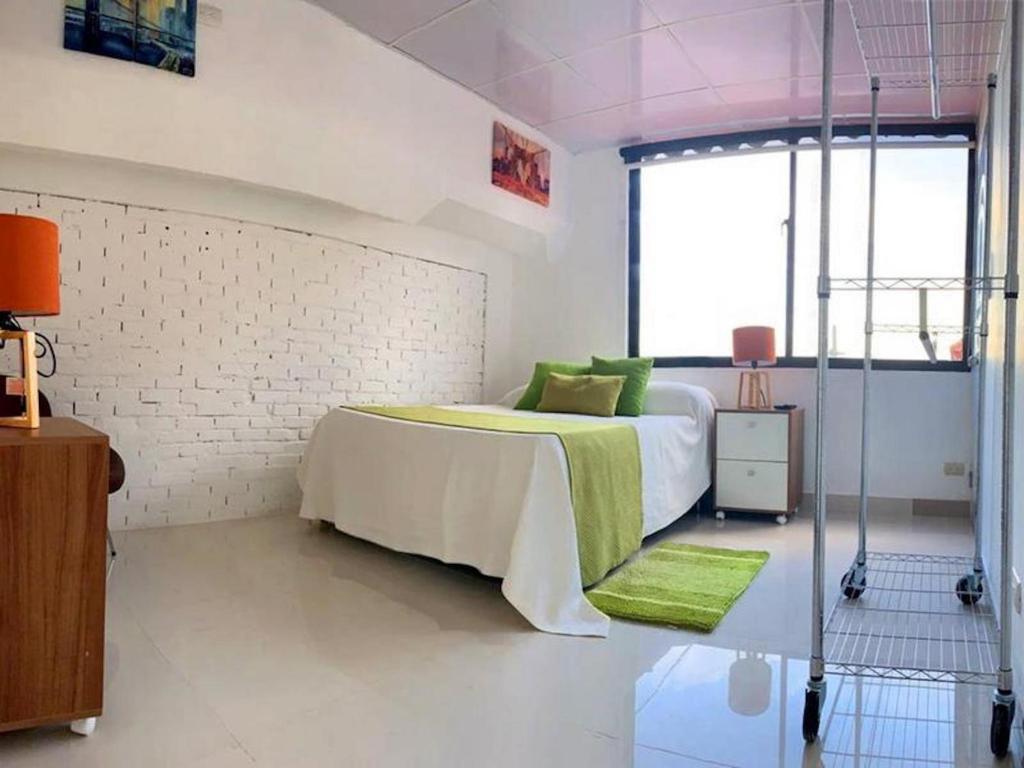 ein Schlafzimmer mit einem Bett mit einer grünen Decke in der Unterkunft Room in Condo - Malecon Premium Rooms in Santo Domingo