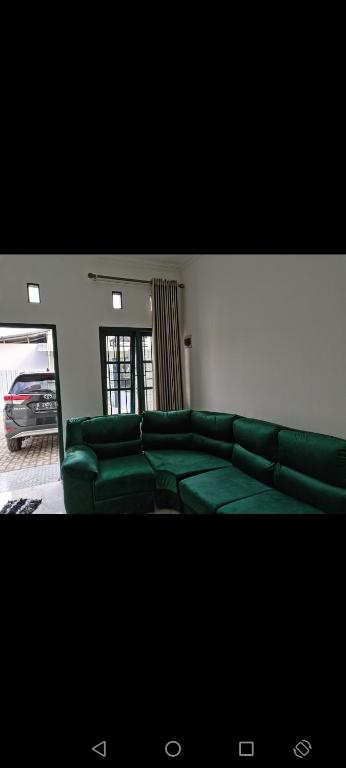 a living room with green leather couches in a room at ZG Homy Jogja in Gondowulung
