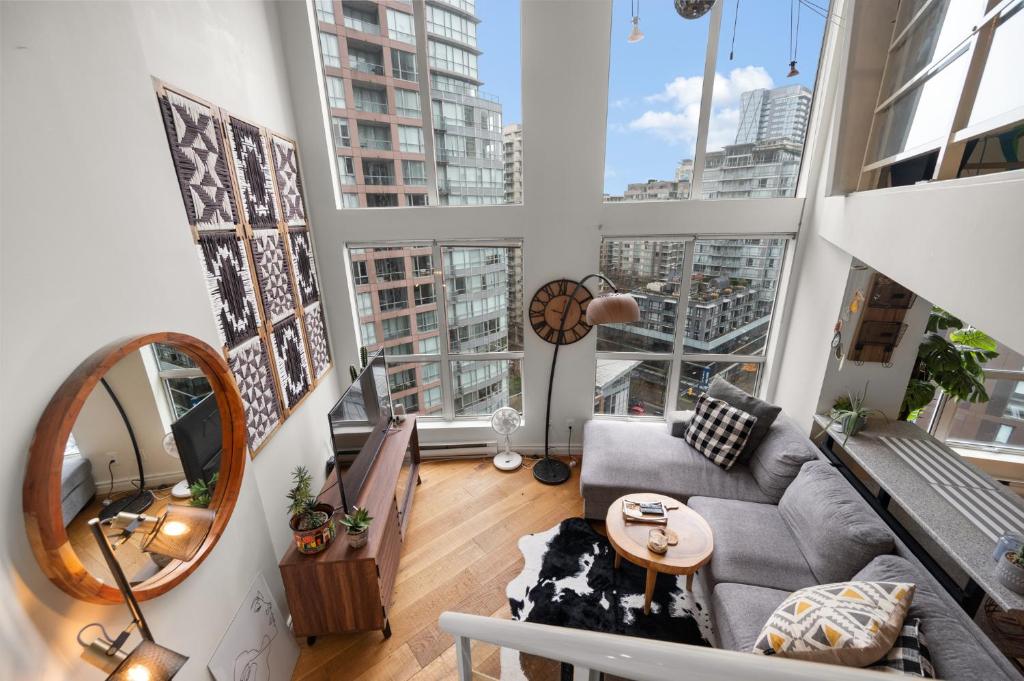 a living room with a couch and a large window at Rare Find Loft with full kitchen at Heart of Downtown in Vancouver