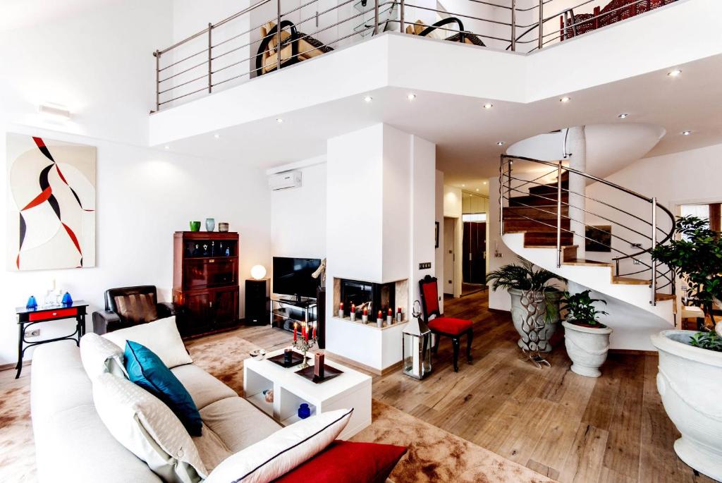 a living room with white furniture and a spiral staircase at Central Stylish Apartments in Budapest