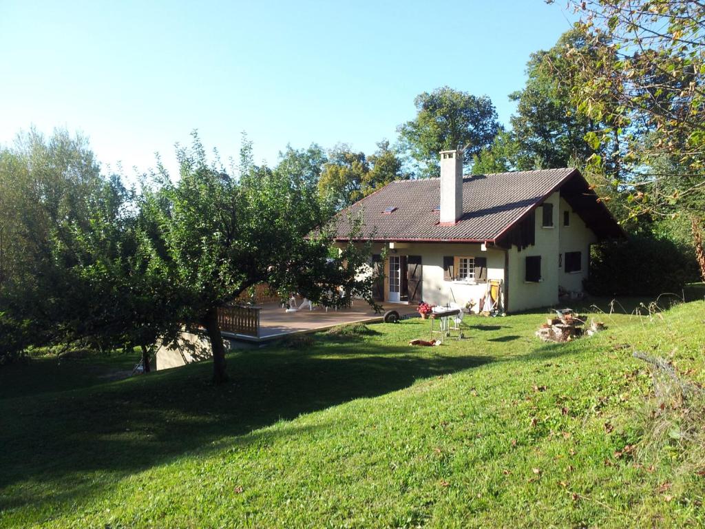 a house on a hill with people sitting in the grass at Holiday home Maison de la litiére in Pugny-Chatenod