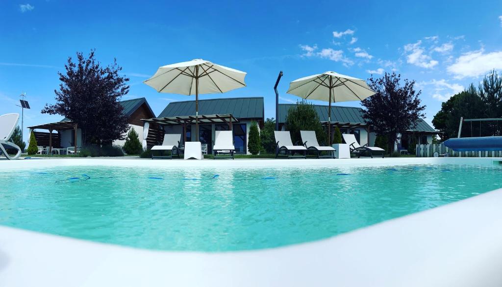 a swimming pool with chairs and umbrellas at Słoneczny Zakątek in Strzeżewo