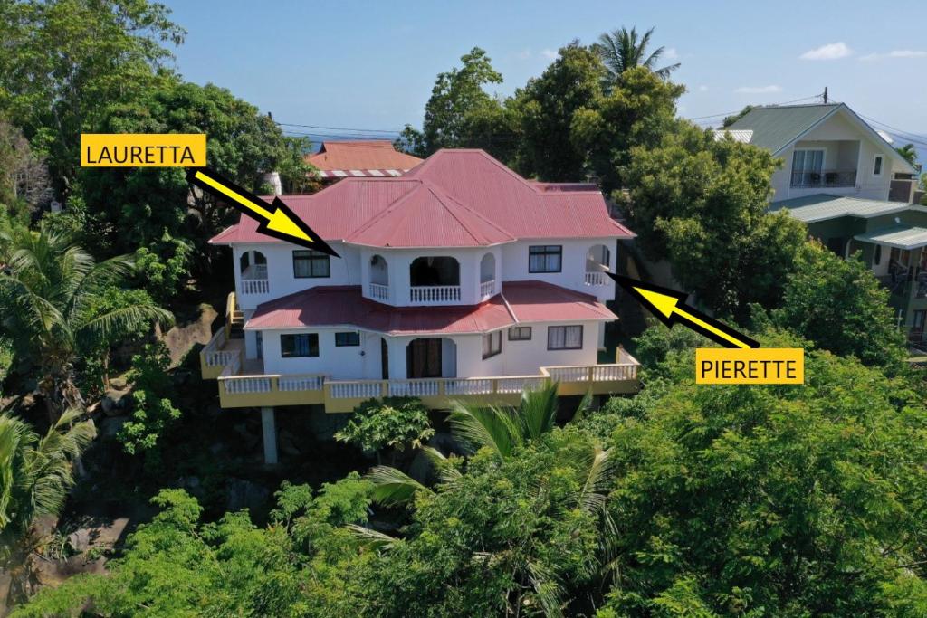 une maison sur le côté d'une colline avec un panneau jaune dans l'établissement Mountain Apartments x4, à Anse Etoile