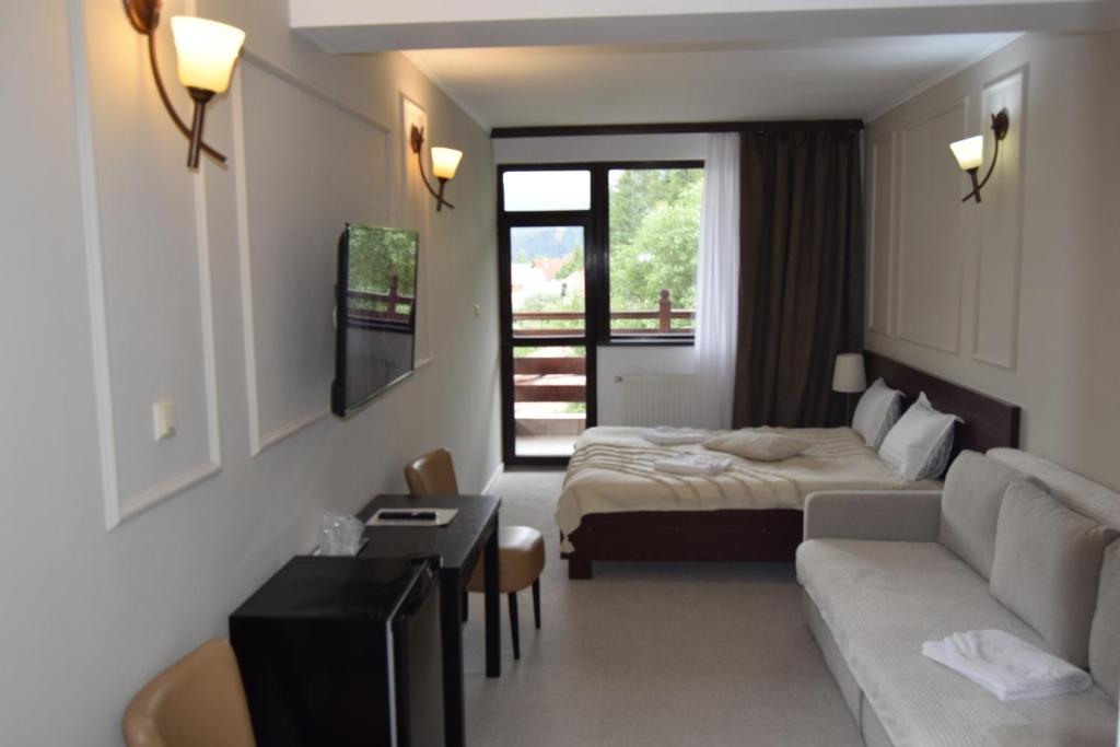 ブシュテニにあるPensiunea Clasicのベッドとソファ付きのホテルルーム