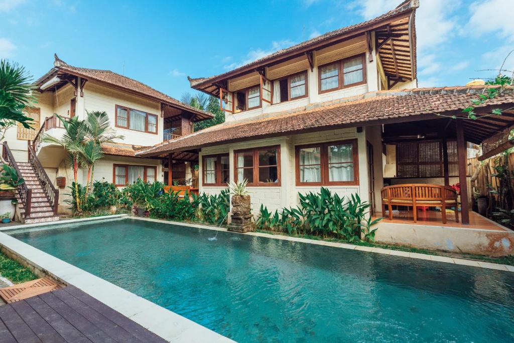 a house with a swimming pool in front of a house at Munari Resort Ubud in Ubud
