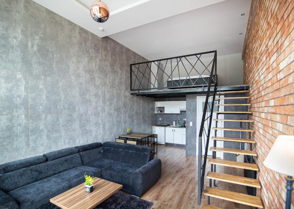 a living room with a blue couch and a brick wall at Apartamenty pod Zamkiem in Łapalice