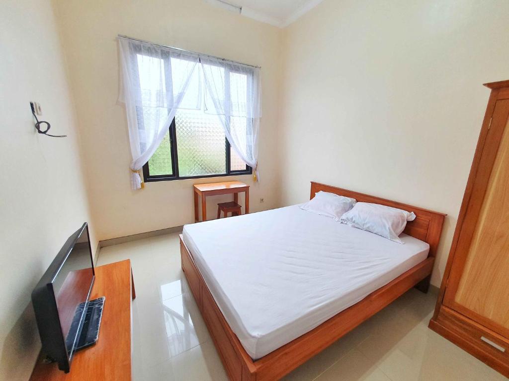 a bedroom with a bed and a tv and a window at Griya Shinta Syariah Solo Mitra RedDoorz in Bonorejo