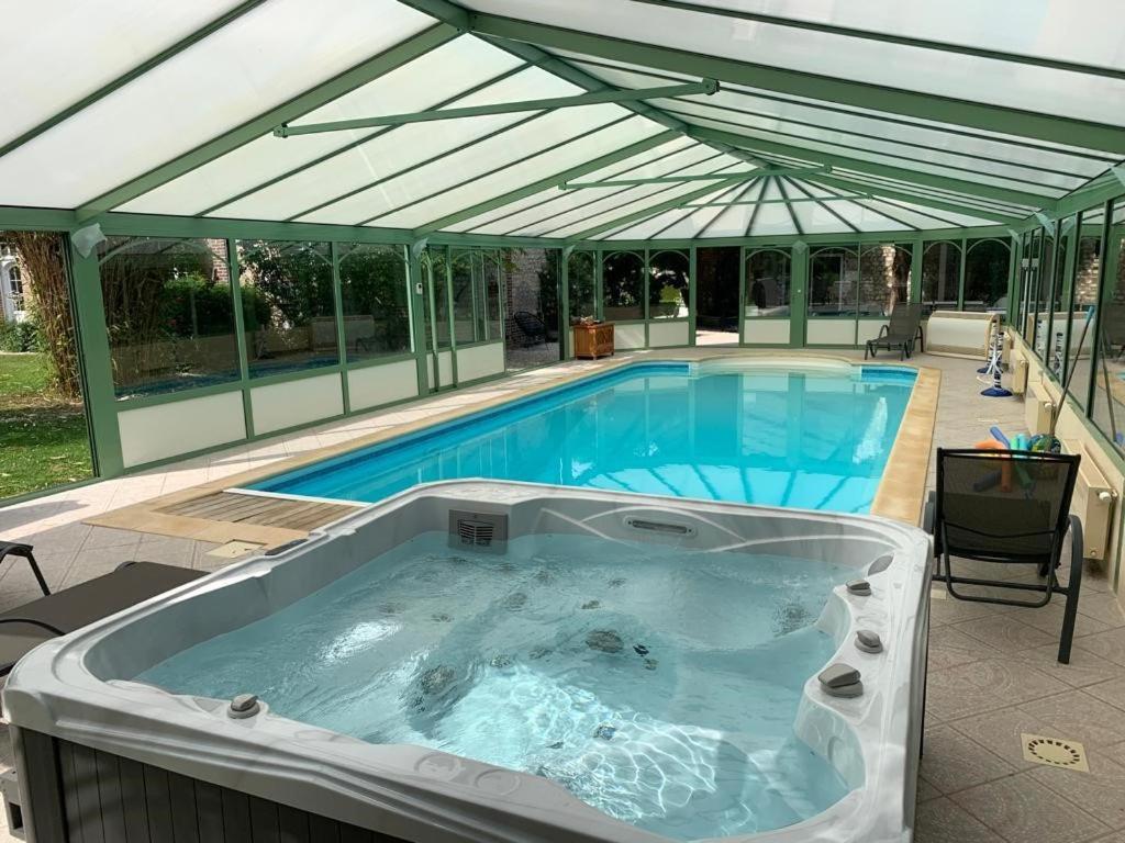 a large hot tub in a patio with an awning at Le Clos des Roches in La Bouille