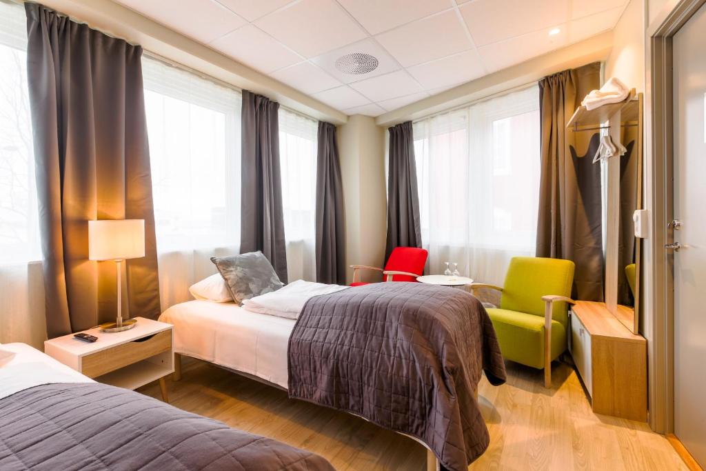 una camera d'albergo con due letti e due sedie di Corner Hotell a Brønnøysund