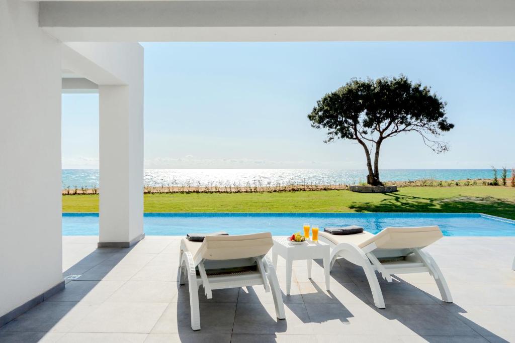 un patio con tavolo, sedie e vista sull'oceano di Seafront Villa Nafsika - Private Heated infinity Pool - Direct access to the beach - Play area a Halikounas