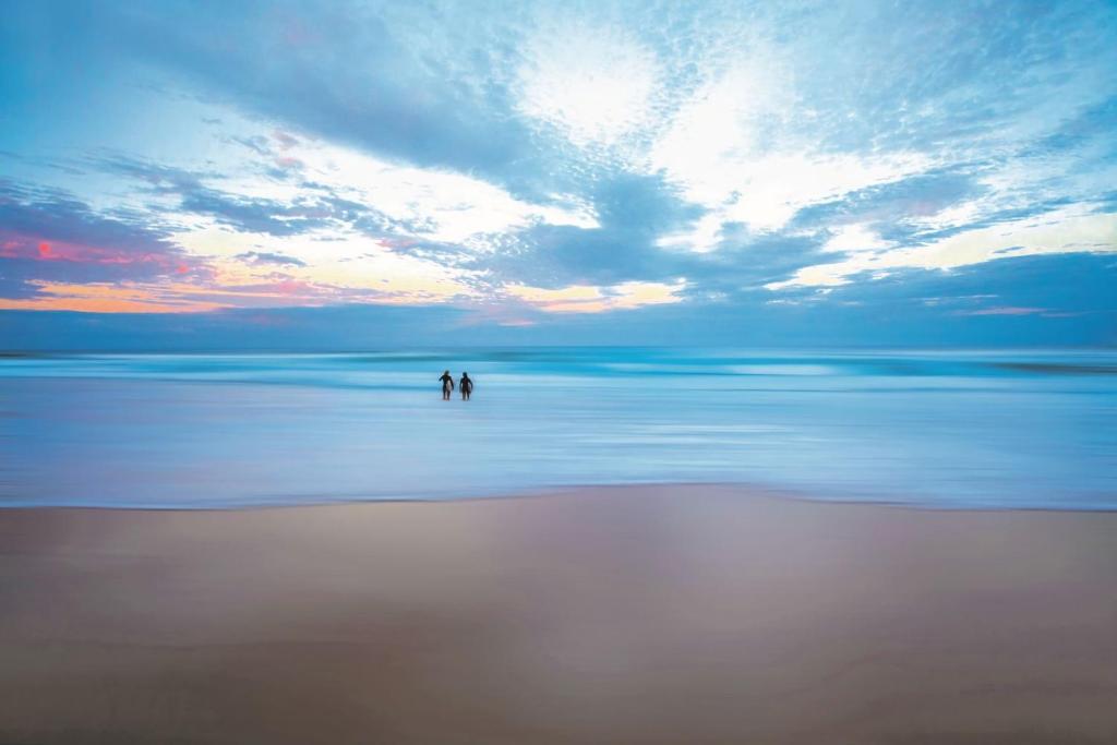 two people standing in the water on a beach at Unit 3 21 Park Generous and Comfortable Beachside Abode in Sunshine Beach