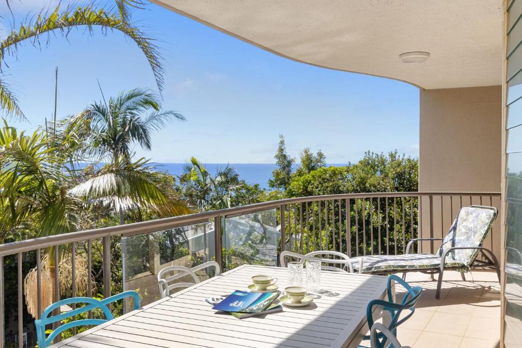 a patio with a table and chairs on a balcony at 5 Pacific Outlook Ocean View Apartment in Sunshine Beach in Sunshine Beach