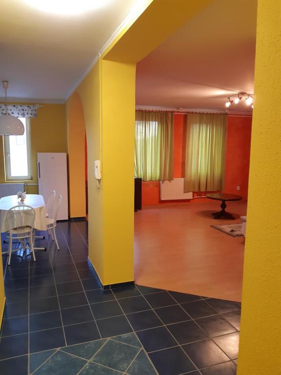un salon avec une table et un mur jaune dans l'établissement Gábor Pál 1 Apartman 1 szoba, à Dunaföldvár