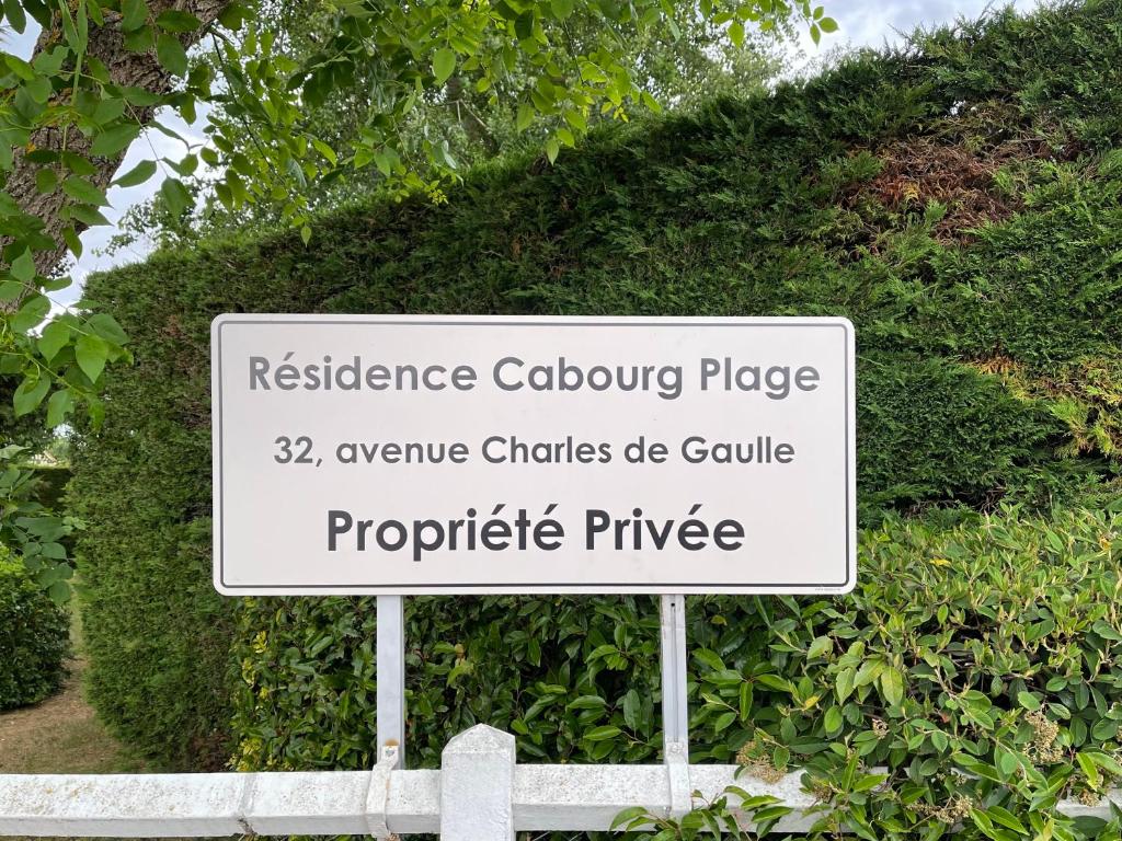 un panneau indiquant un emplacement pavé de référence devant une haie dans l'établissement Cabourg plage à 200m plage, à Cabourg