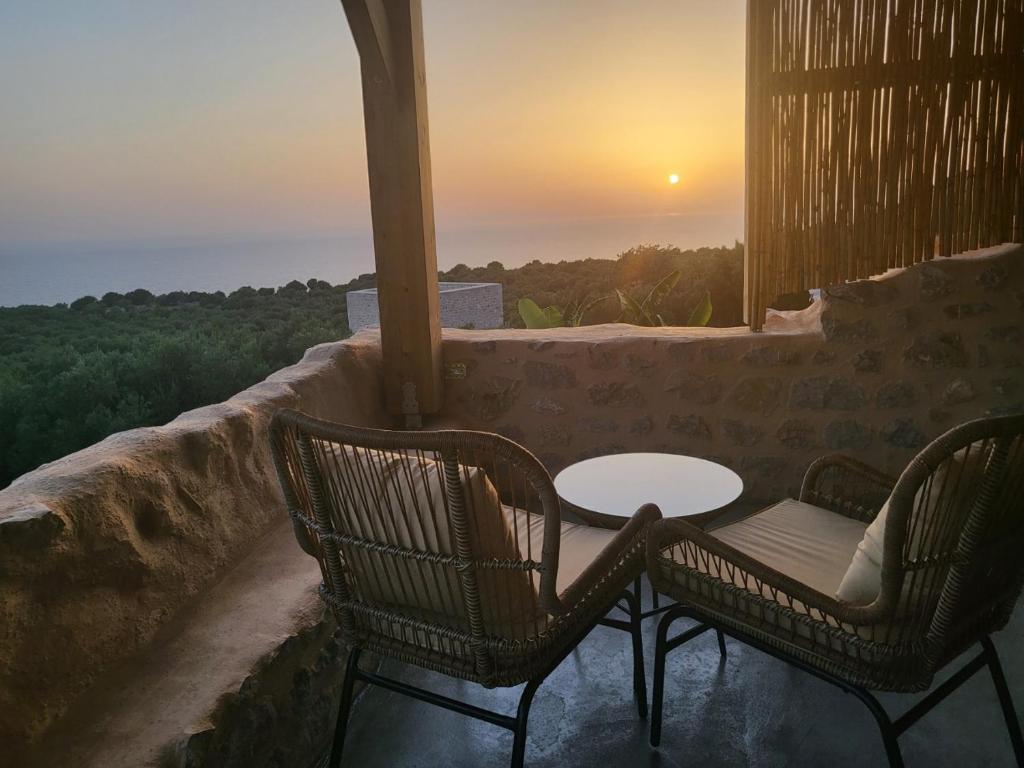 una mesa y sillas en un balcón con vistas a la puesta de sol en VillaAurora-mani, en Areopoli