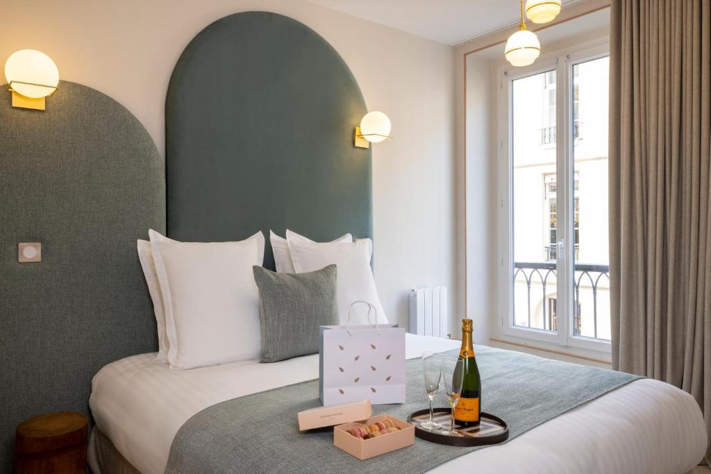 um quarto de hotel com uma cama e uma garrafa de champanhe em Yuna Saint-Honoré - Serviced Apartments em Paris