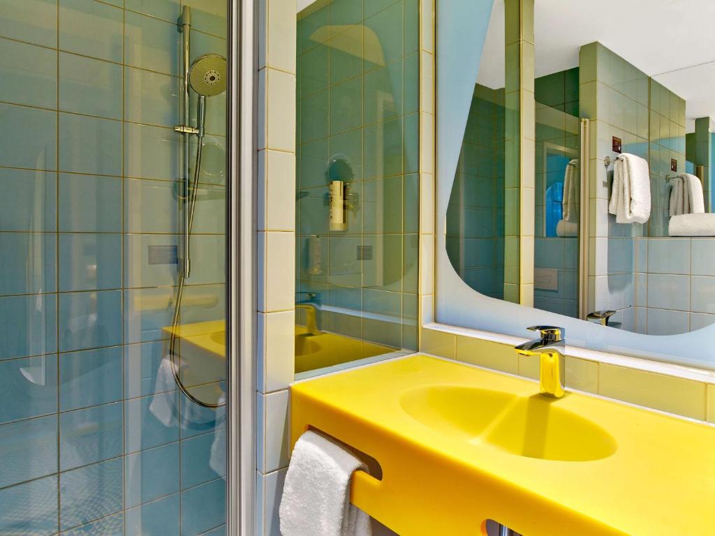 a bathroom with a yellow sink and a mirror at prizeotel Hannover-City in Hannover