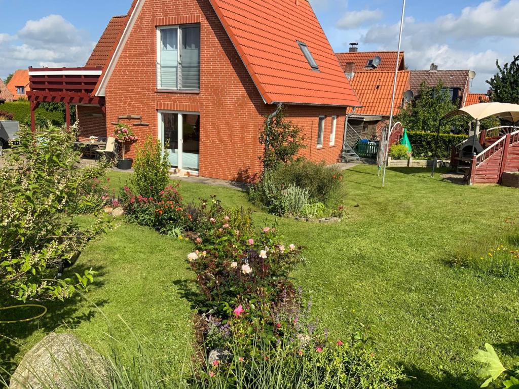 a house with an orange roof and a yard with flowers at Ankerplatz in Winnemark