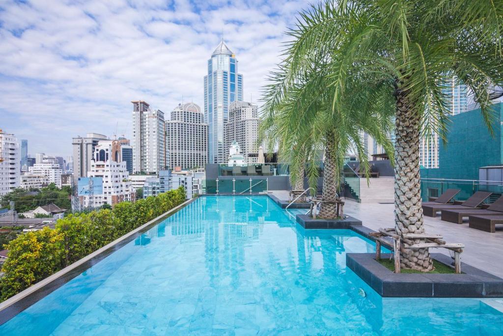 a swimming pool with palm trees on top of a building at SureStay Plus Hotel by Best Western Sukhumvit 2 in Bangkok