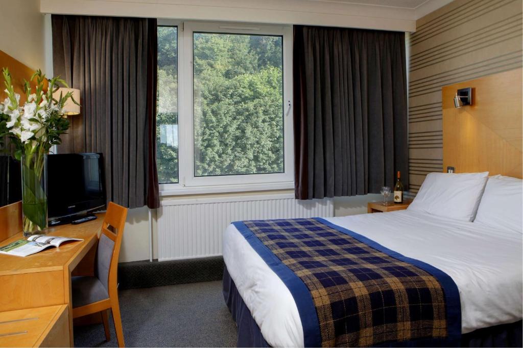 ein Hotelzimmer mit einem Bett, einem Schreibtisch und einem TV in der Unterkunft Best Western Palace Hotel & Casino in Douglas