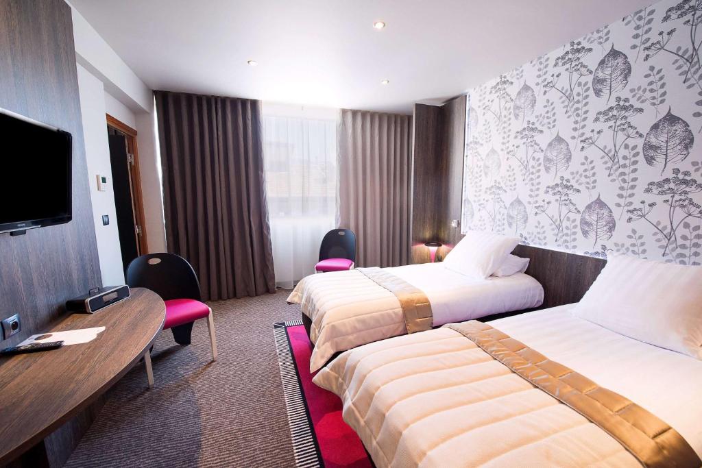 a hotel room with two beds and a flat screen tv at Best Western Premier Le Patio des Artistes Wellness Jacuzzi in Cannes