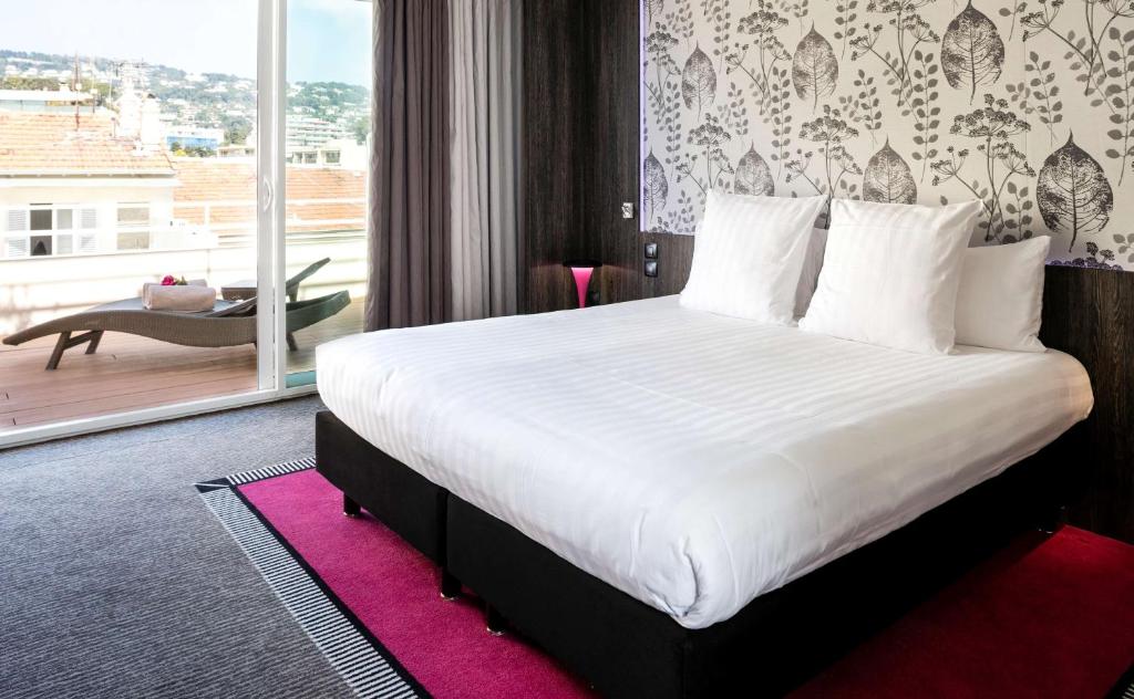 a bedroom with a large bed and a large window at Best Western Premier Le Patio des Artistes Wellness Jacuzzi in Cannes