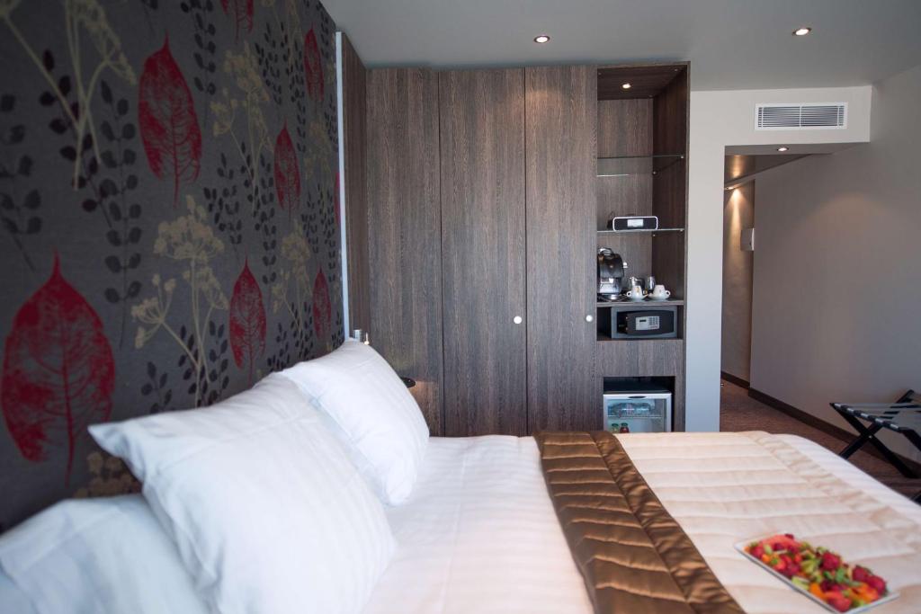 a bedroom with a large bed with white pillows at Best Western Premier Le Patio des Artistes Wellness Jacuzzi in Cannes