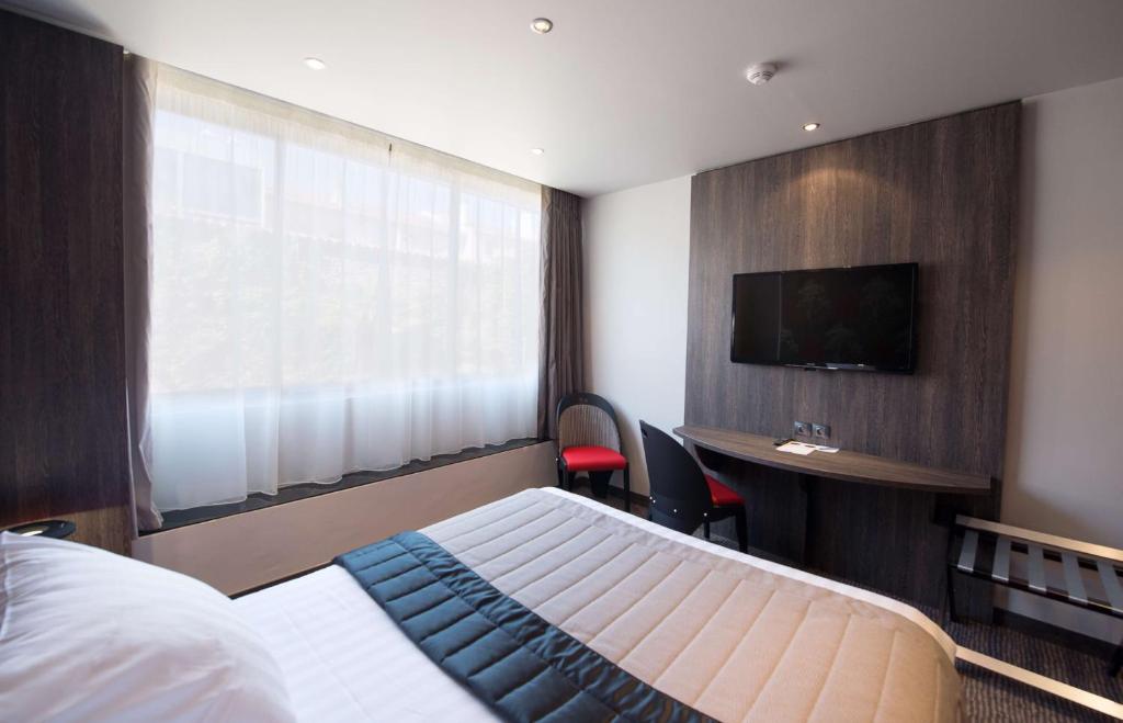 a bedroom with a bed and a desk and a television at Best Western Premier Le Patio des Artistes Wellness Jacuzzi in Cannes