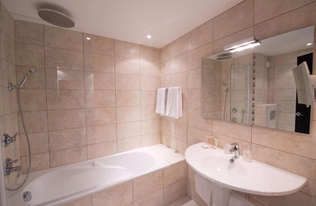 a bathroom with a tub and a sink and a shower at Best Western Premier Le Patio des Artistes Wellness Jacuzzi in Cannes