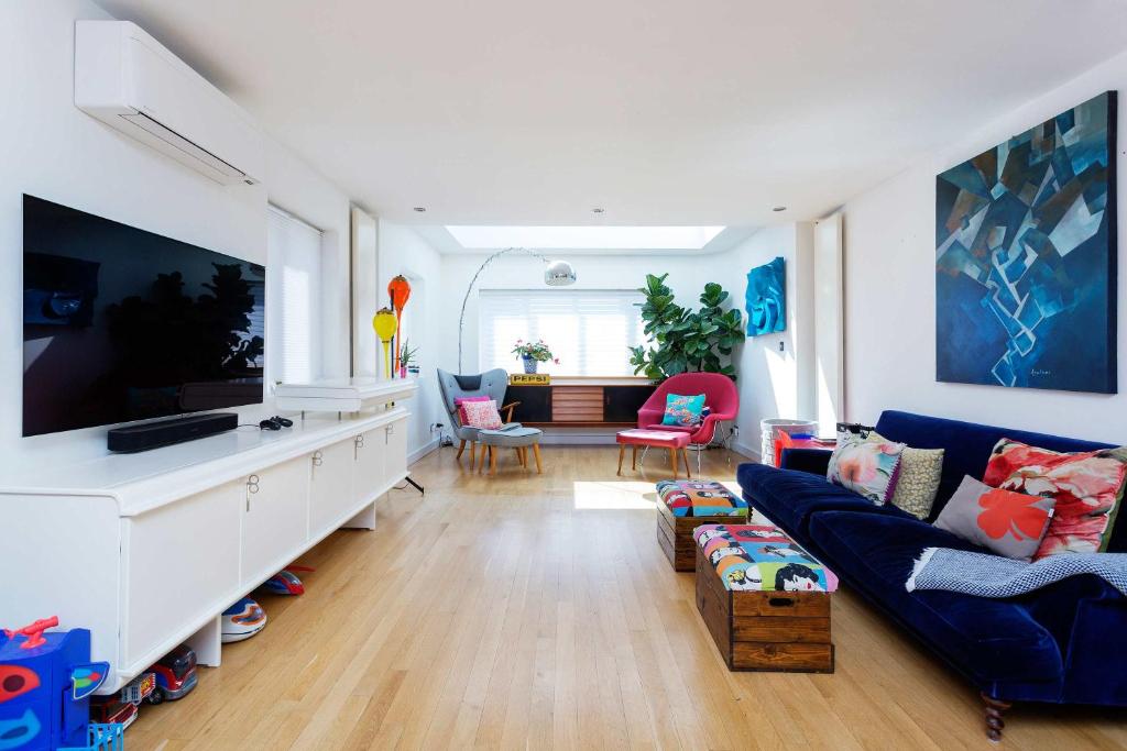 a living room with a blue couch and a tv at Veeve - Rubix Cube Mews in London