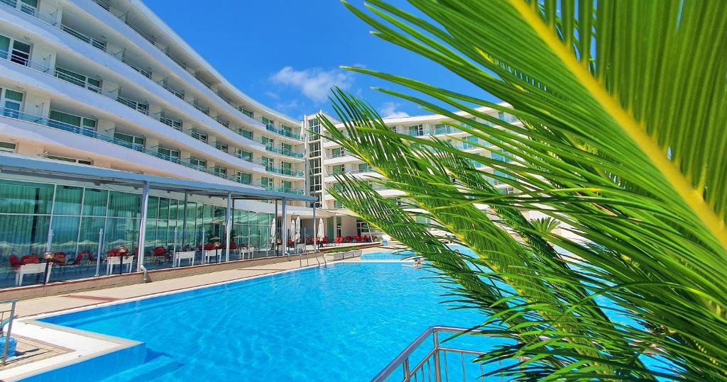 uma palmeira em frente a um edifício com piscina em Festa Panorama Hotel em Nessebar