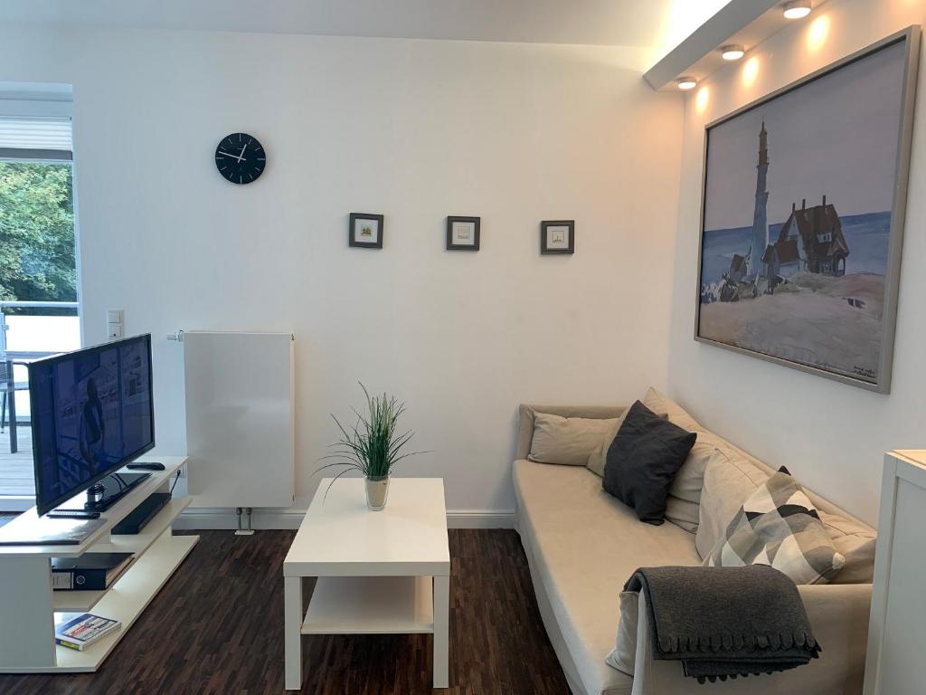 un soggiorno bianco con divano e TV di Ferienwohnung "Im Bad 40a - Wohnung 4" a Sankt Peter-Ording