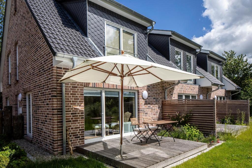 a patio with a table and an umbrella at Ferienhaus DHH SKILLEHUS in Tating