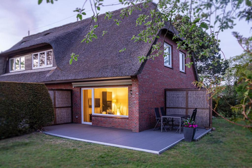 a brick house with a large window and a patio at Ferienhaus RH "Achter de Dün" in Sankt Peter-Ording