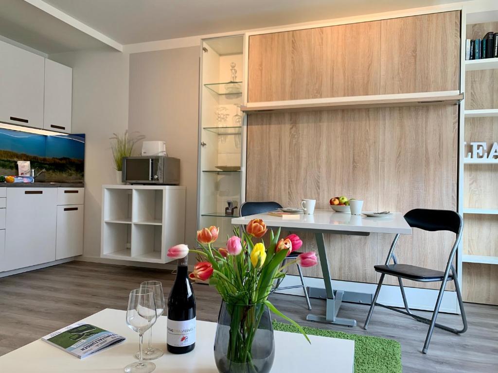 una sala de estar con una mesa con un jarrón de flores en Ferienwohnung "Dünennest", en Sankt Peter-Ording