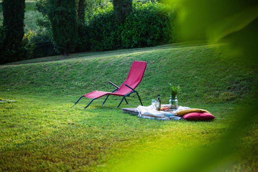 una silla rosa sentada en el césped con una mesa en Via Francigena Cottage in the Green en San Gimignano