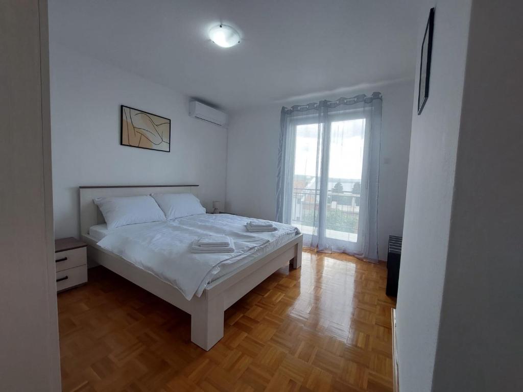 - une chambre blanche avec un lit et une fenêtre dans l'établissement Violeta, à Crikvenica