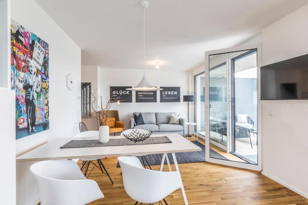 a dining room and living room with a white table and chairs at Penthouse Ferienwohnung in Bahlingen