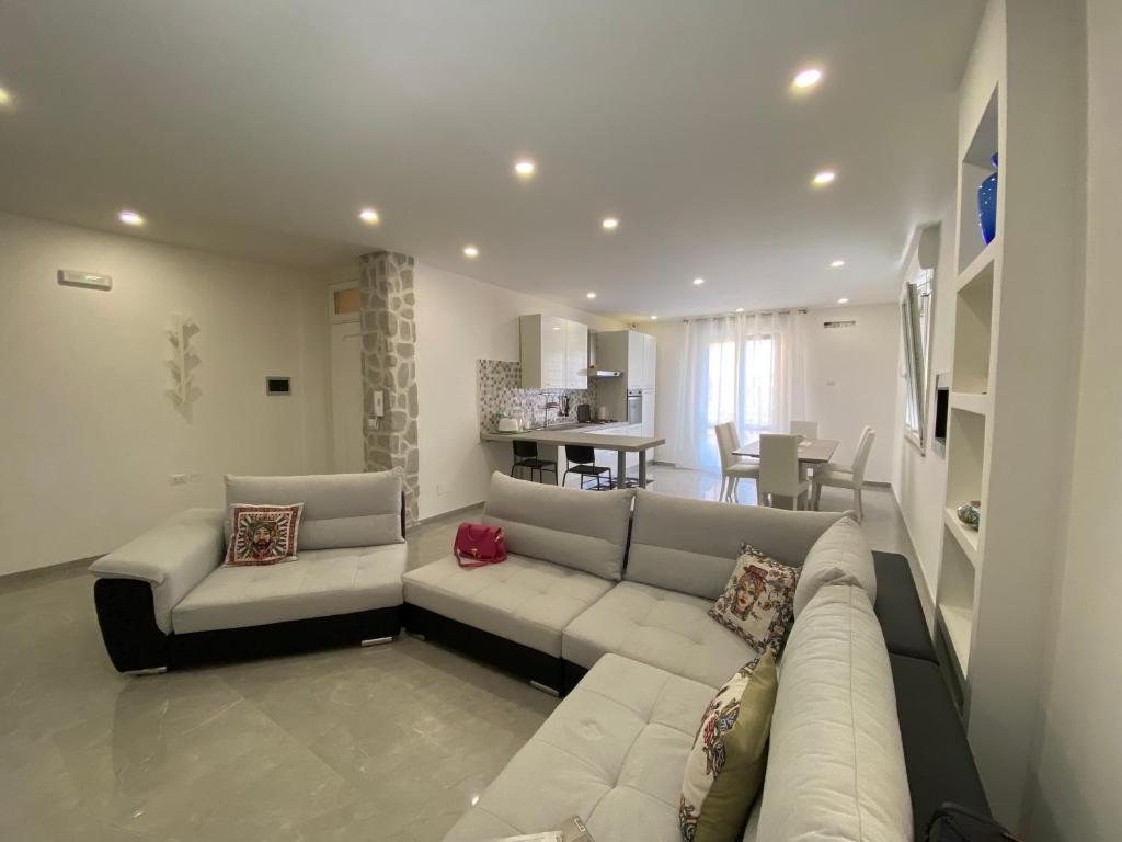 a living room with a white couch and a kitchen at Melitta apartment Giardini Naxos in Giardini Naxos