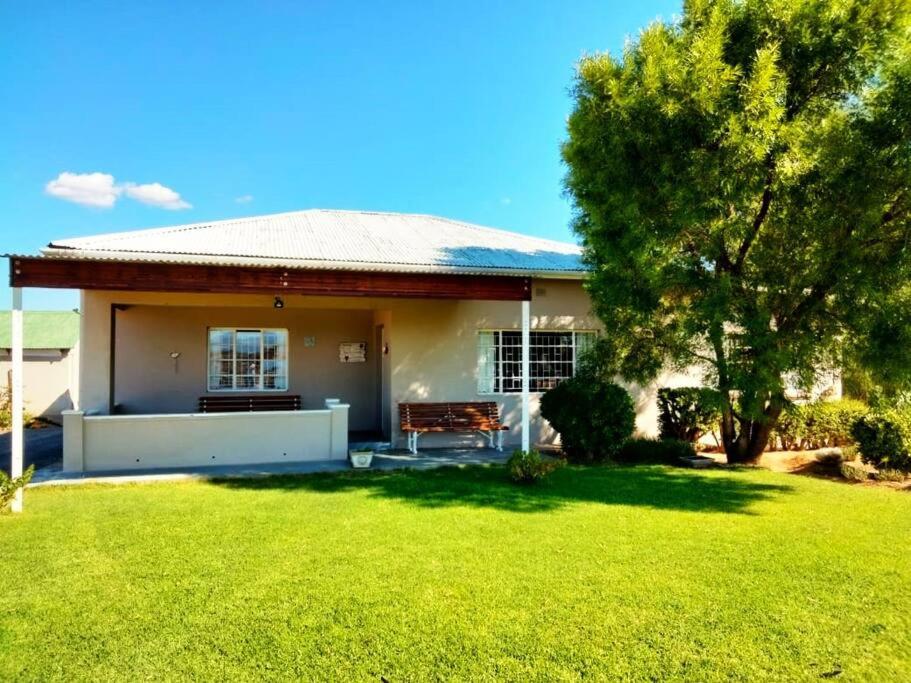 uma pequena casa com um banco num quintal em Sunnyside Farm Cottage, Oudtshoorn, South Africa em Oudtshoorn