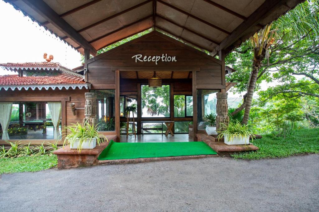 una casa con una alfombra verde delante de ella en Stone Water Eco Resort en Bogmalo
