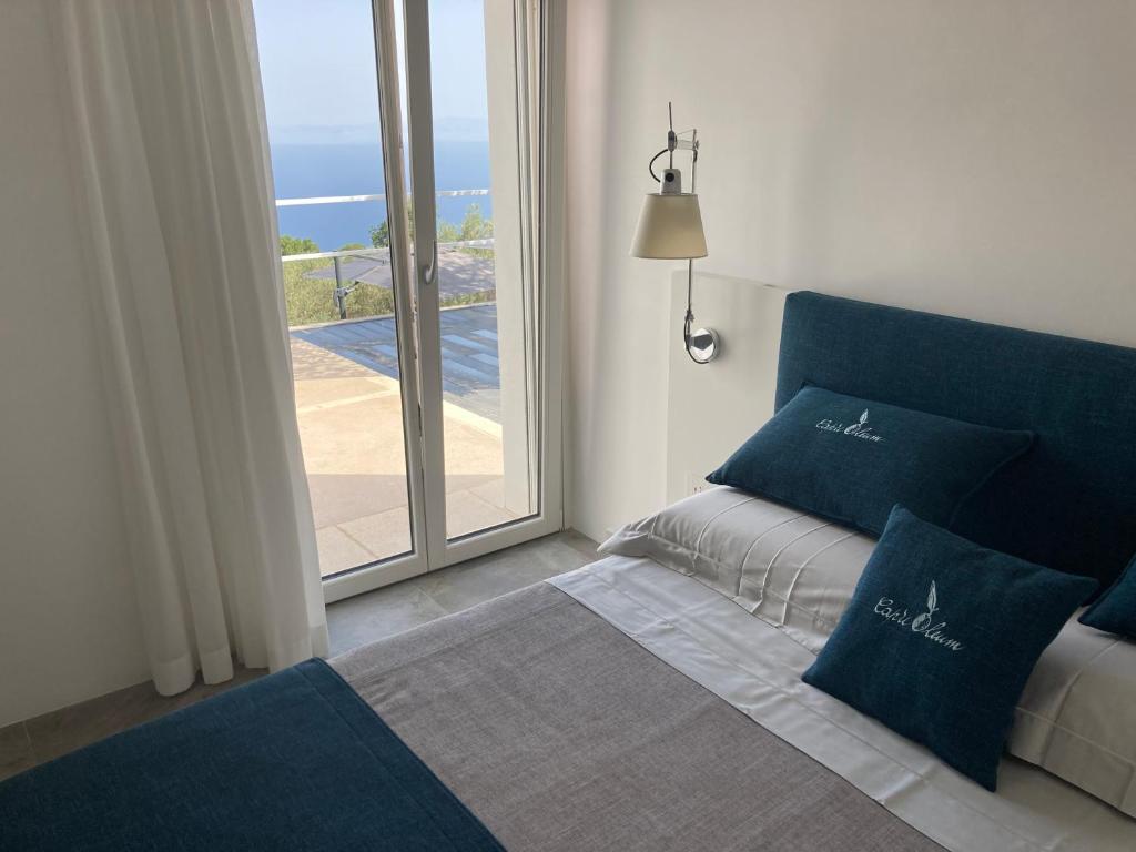 a bed with blue pillows in a room with a window at “CapriOleum” esclusive place in Anacapri
