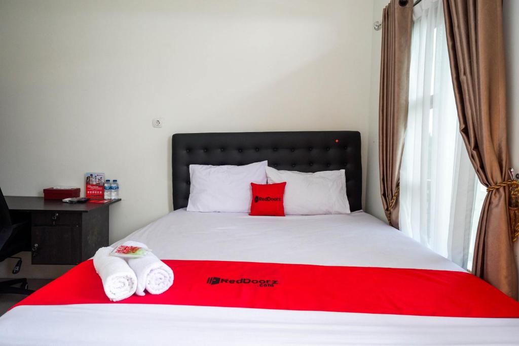 a bed with two red pillows and a red blanket at RedDoorz Syariah near RS Hermina Yogyakarta in Seturan